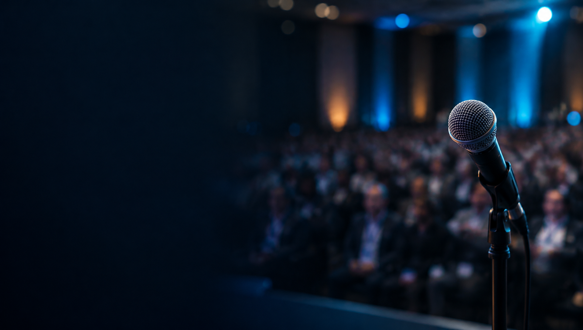 View from a keynote stage, microphone in focus with a blurred audience
